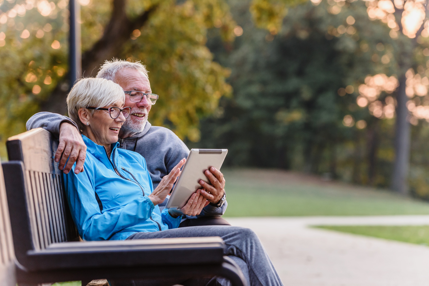 smiling couple on a bench looking at an ipad to preplan funeral